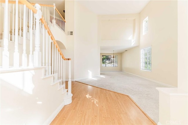 interior space with baseboards, a towering ceiling, stairway, wood finished floors, and carpet floors