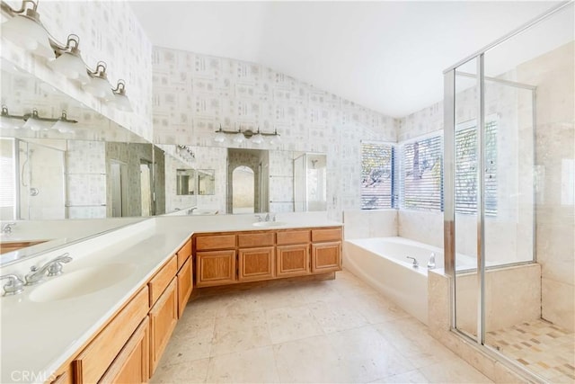 bathroom featuring a stall shower, vaulted ceiling, a garden tub, and a sink