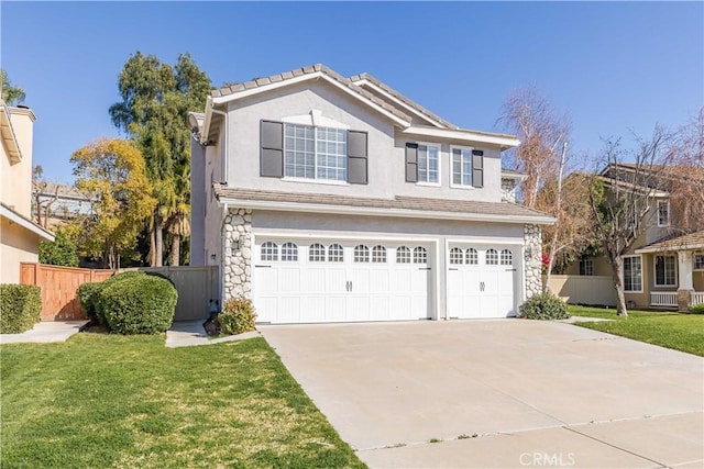 traditional-style home with a garage, fence, stone siding, concrete driveway, and a front yard