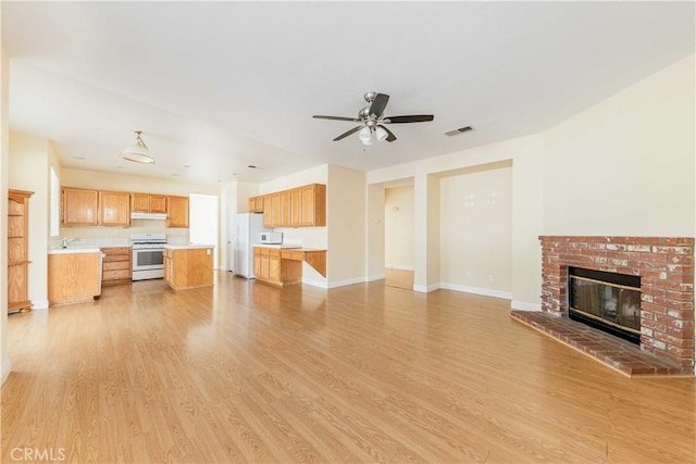 unfurnished living room featuring light wood-style floors, visible vents, a fireplace, and baseboards