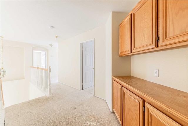 corridor featuring light colored carpet and an upstairs landing