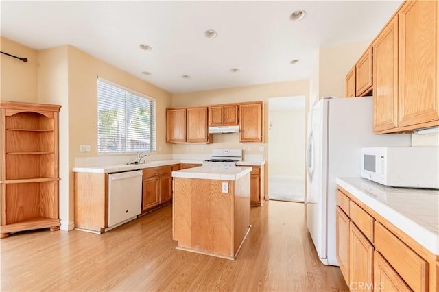 kitchen featuring white appliances, light wood-style floors, a center island, light countertops, and under cabinet range hood