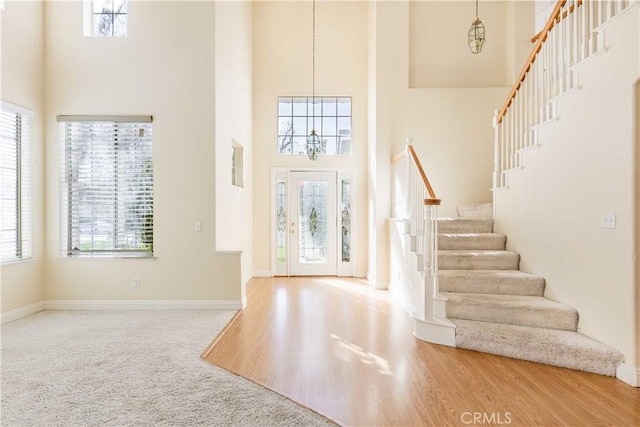 foyer with baseboards, stairway, a high ceiling, and wood finished floors