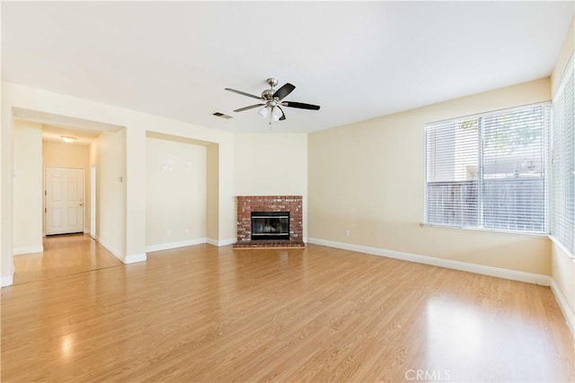 unfurnished living room featuring ceiling fan, a fireplace, visible vents, baseboards, and light wood-style floors