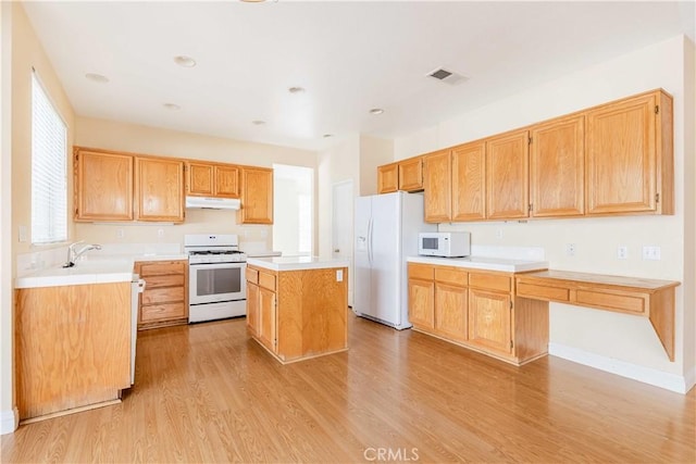 kitchen featuring white appliances, under cabinet range hood, light countertops, and a center island