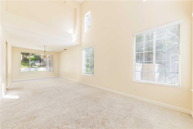 carpeted spare room featuring a high ceiling and baseboards