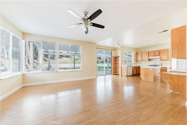 unfurnished living room with light wood-style flooring, a ceiling fan, visible vents, and baseboards