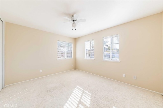 spare room with light colored carpet, plenty of natural light, and ceiling fan