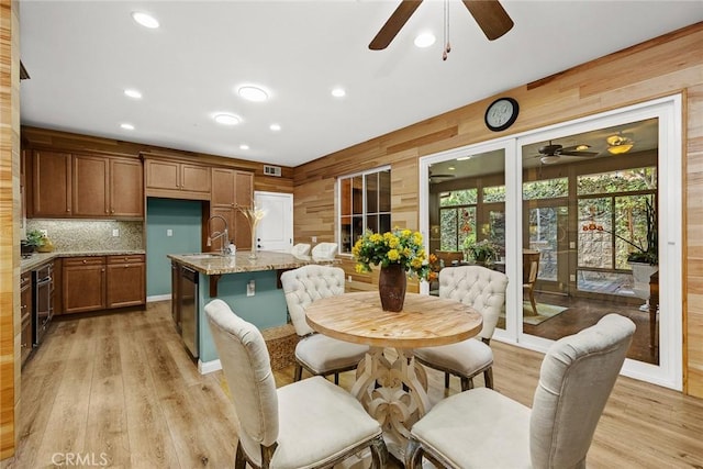 dining area with wooden walls, recessed lighting, visible vents, and light wood-style floors