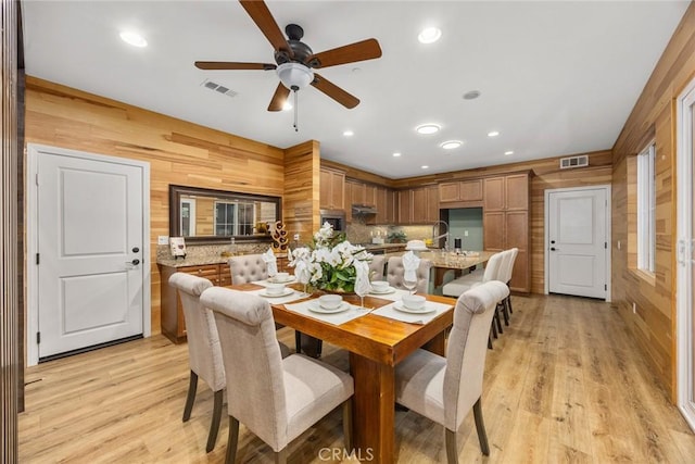 dining space featuring light wood-style floors, recessed lighting, visible vents, and wooden walls