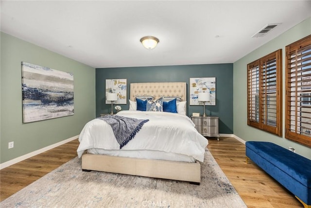 bedroom featuring visible vents, baseboards, and wood finished floors