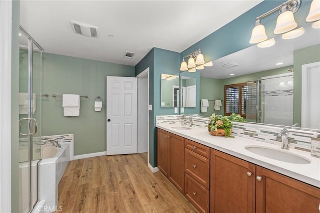 bathroom featuring a garden tub, wood finished floors, a sink, visible vents, and a shower stall