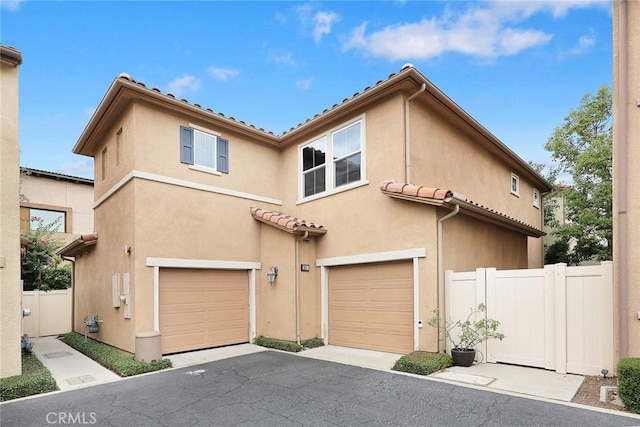 mediterranean / spanish-style house featuring a garage, a tile roof, fence, and stucco siding