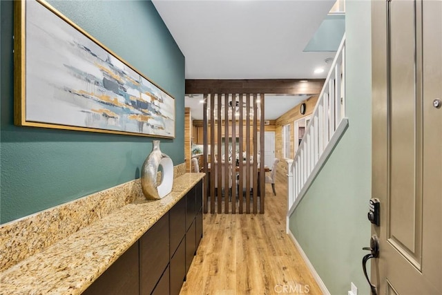 corridor with light wood finished floors, stairway, and baseboards