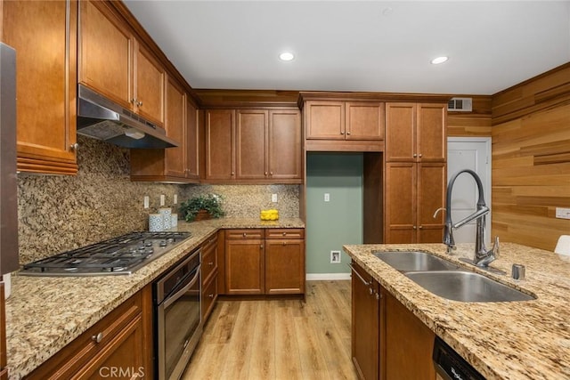 kitchen featuring tasteful backsplash, visible vents, stainless steel appliances, under cabinet range hood, and a sink