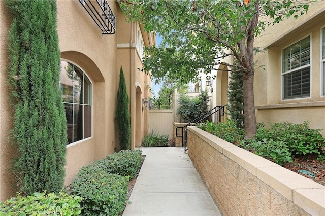 view of side of home with fence and stucco siding