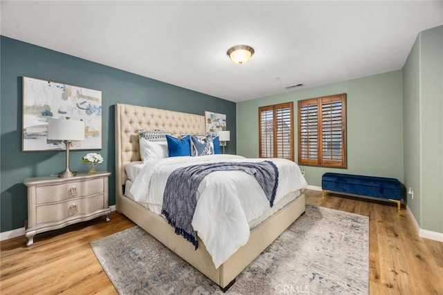 bedroom with wood finished floors, visible vents, and baseboards