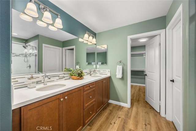 bathroom featuring wood finished floors, a stall shower, a sink, and decorative backsplash