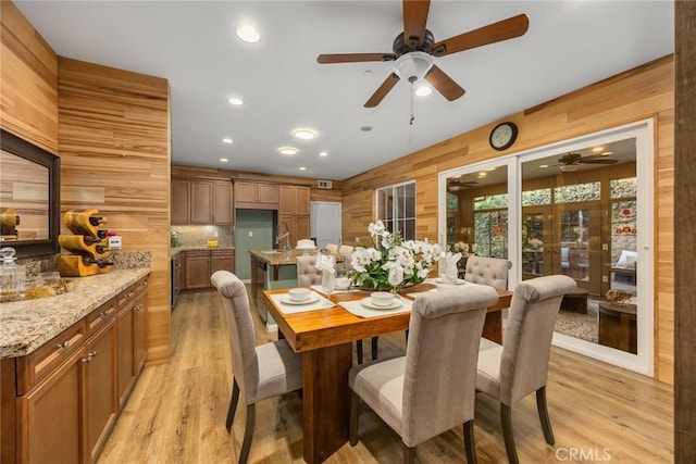 dining area featuring wood walls, light wood-style flooring, and recessed lighting