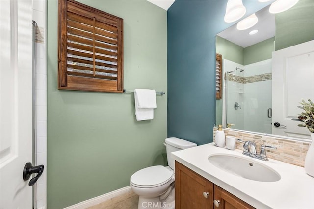 bathroom featuring a stall shower, baseboards, toilet, vanity, and backsplash