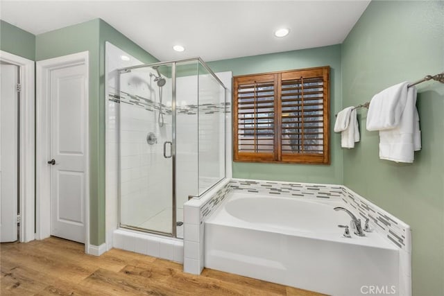 full bathroom with recessed lighting, a shower stall, a bath, and wood finished floors