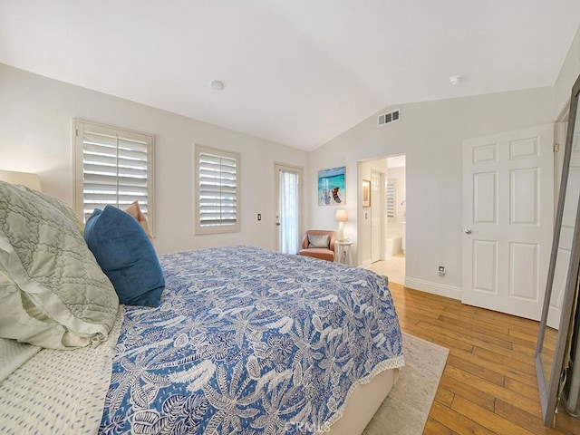 bedroom with lofted ceiling, visible vents, ensuite bathroom, light wood-type flooring, and baseboards