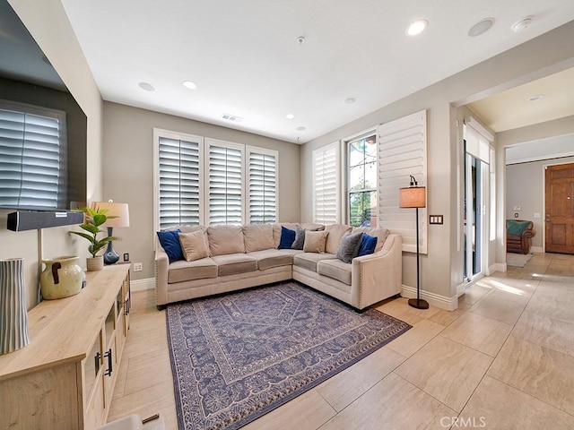 living area with baseboards, visible vents, and recessed lighting