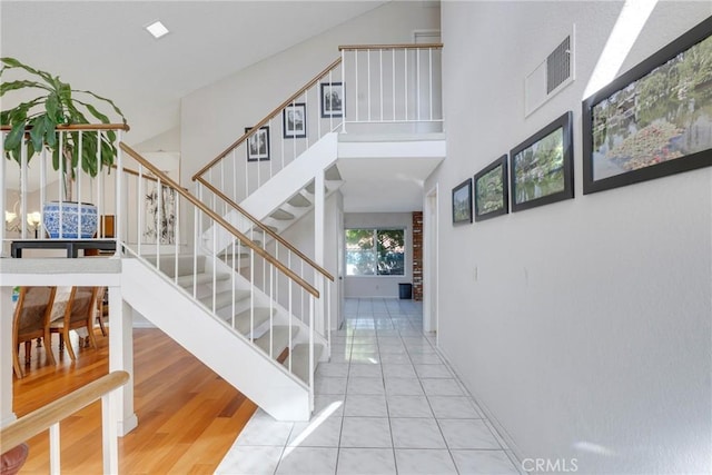 stairway featuring a high ceiling, tile patterned flooring, and visible vents