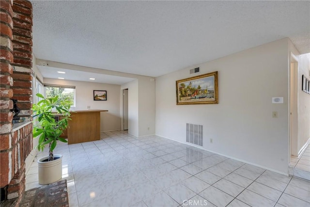 unfurnished living room featuring visible vents, a textured ceiling, baseboards, and light tile patterned floors