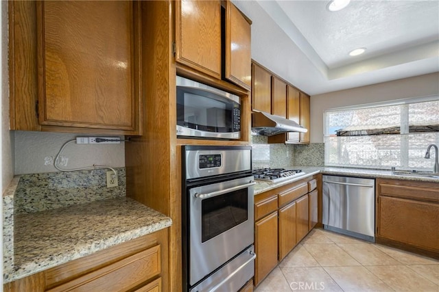 kitchen with tasteful backsplash, appliances with stainless steel finishes, under cabinet range hood, a sink, and a warming drawer