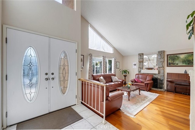 foyer featuring high vaulted ceiling, french doors, and light wood-type flooring