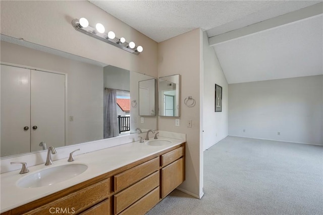 full bath with vaulted ceiling with beams, a textured ceiling, double vanity, and a sink