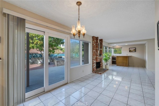 interior space featuring a textured ceiling, a chandelier, light tile patterned flooring, beverage cooler, and a fireplace