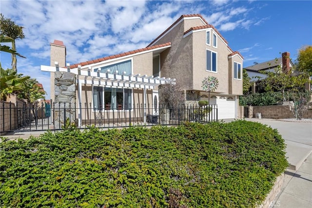 view of front of home featuring an attached garage, a tile roof, concrete driveway, a pergola, and stucco siding