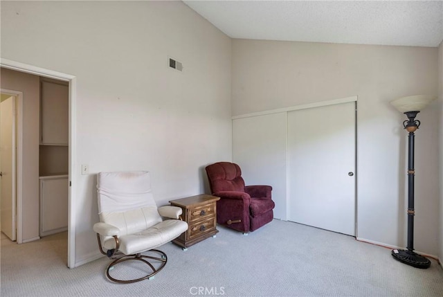 living area with visible vents, vaulted ceiling, and light colored carpet