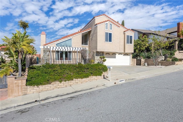 view of front of property with a garage, fence, concrete driveway, a tiled roof, and stucco siding