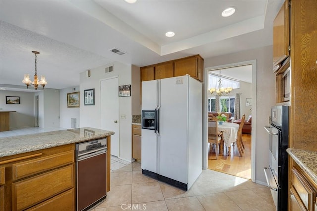 kitchen featuring visible vents, brown cabinetry, hanging light fixtures, an inviting chandelier, and white fridge with ice dispenser