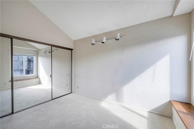 empty room with lofted ceiling, a textured ceiling, and carpet