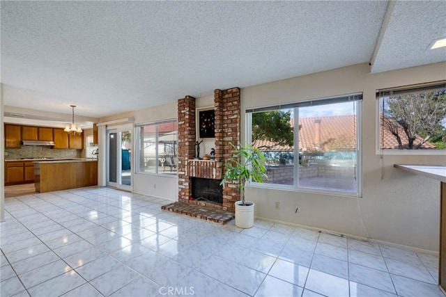 unfurnished living room with a brick fireplace, light tile patterned floors, baseboards, and an inviting chandelier