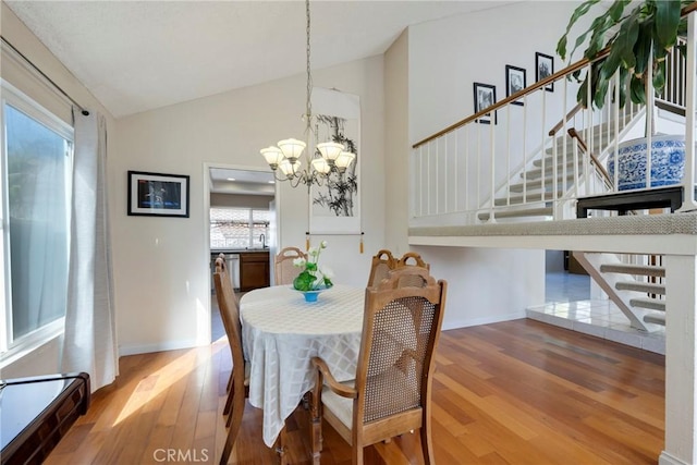 dining area with baseboards, stairway, wood finished floors, and an inviting chandelier