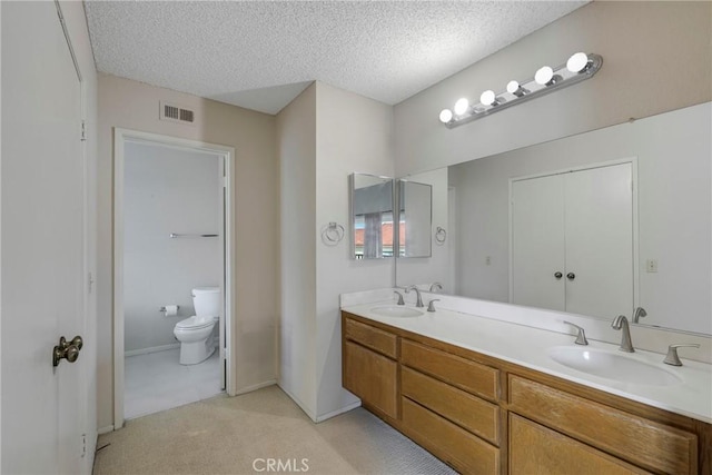 bathroom with visible vents, a sink, toilet, and double vanity