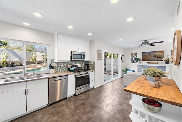 kitchen featuring stainless steel appliances, white cabinets, a sink, and backsplash