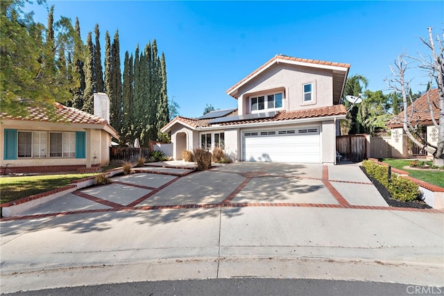 view of front of house with driveway, a tile roof, fence, and solar panels