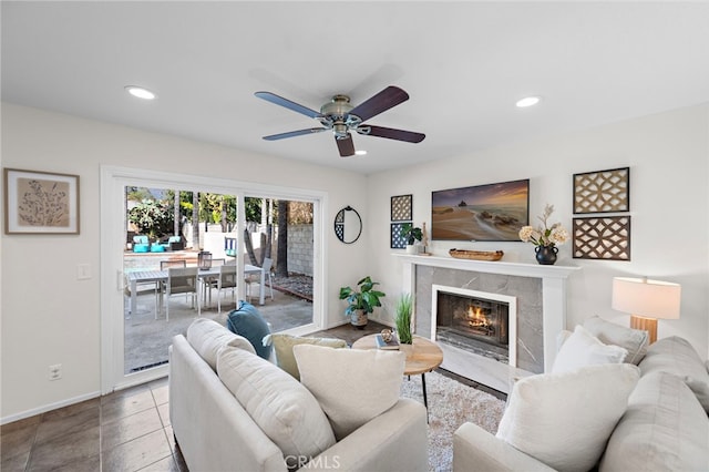 living area featuring tile patterned flooring, recessed lighting, a premium fireplace, a ceiling fan, and baseboards