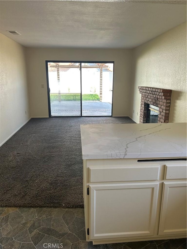 25239 Madrone Dr, Murrieta, CA 92563 - unfurnished living room with a brick fireplace, dark carpet, a textured ceiling, and a textured wall
