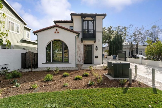 view of front of house with a tiled roof, fence, a gate, and stucco siding