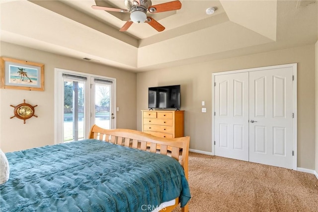 carpeted bedroom featuring access to exterior, ceiling fan, baseboards, and a raised ceiling