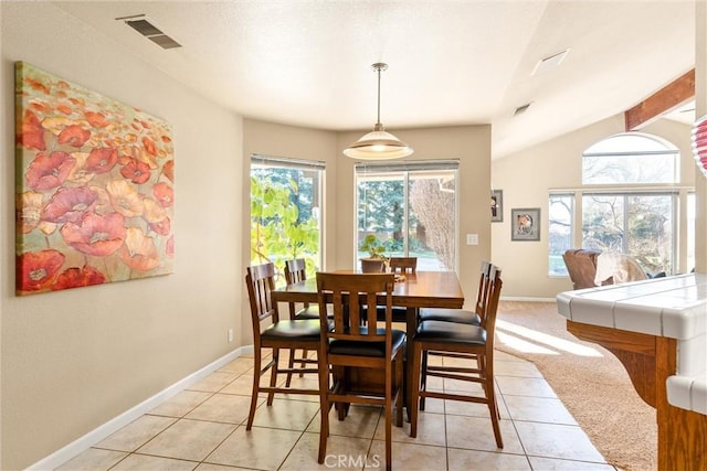 dining area featuring vaulted ceiling, light tile patterned flooring, visible vents, and baseboards