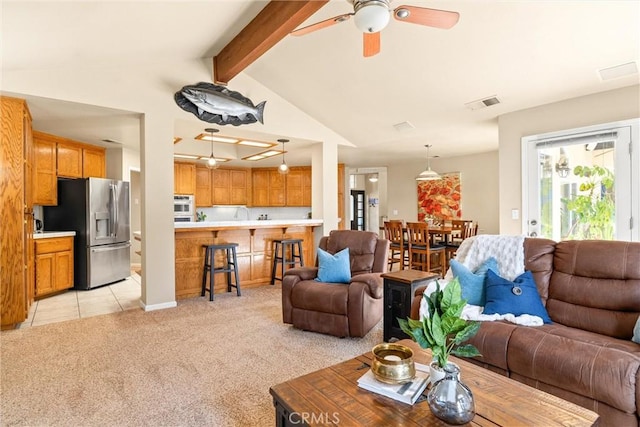 living area with vaulted ceiling with beams, light tile patterned floors, light colored carpet, visible vents, and a ceiling fan