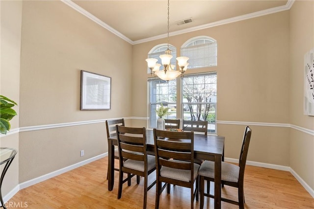 dining room featuring a chandelier, baseboards, visible vents, and light wood-style floors